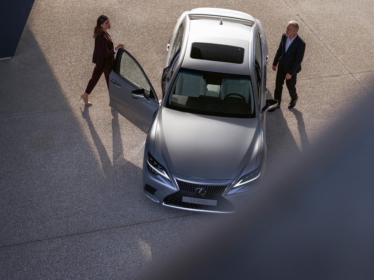 A woman and man walking towards a parked Lexus LS