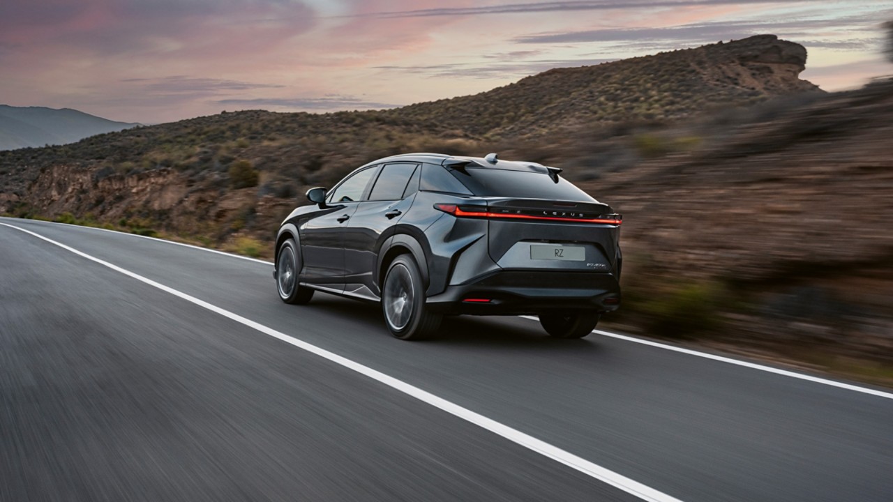 Rear view of the Lexus RZ 450e driving in a rural location